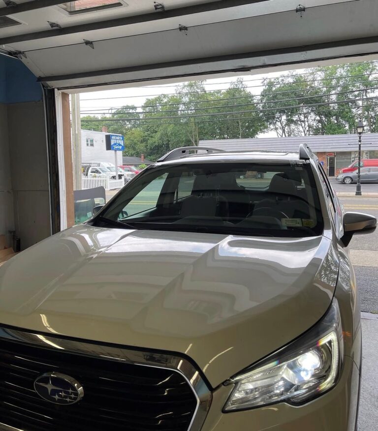 White Subaru Forester receiving professional windshield replacement service at an auto glass shop serving Mineola, NY.