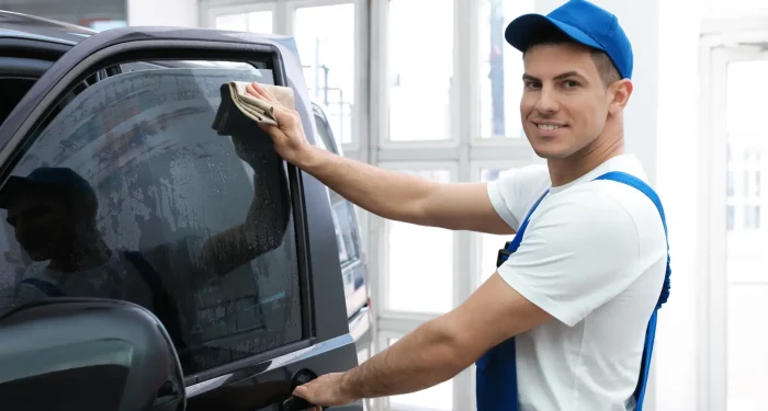 Auto glass professional performing a final inspection and cleaning after vehicle window replacement.